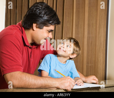 Hispanic father and son doing homework and making eye contact Stock Photo