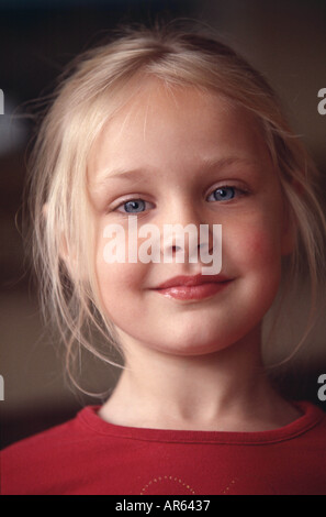 Female child blonde hair off face strands framing face wearing red top looking to camera smiling Stock Photo