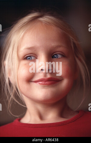 Female child blonde hair off face strands framing face wearing red top looking to side smiling Stock Photo