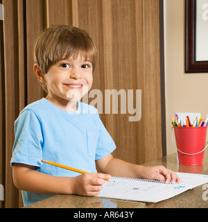 Hispanic boy smiling at viewer and doing homework Stock Photo