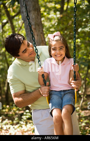 Hispanic father pushing daughter on swing Stock Photo