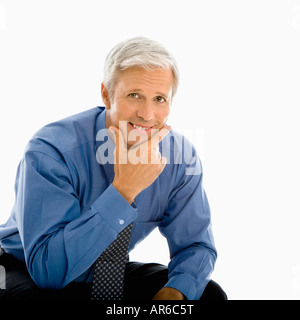 Middle aged Caucasian man smiling at viewer with hand to chin Stock Photo