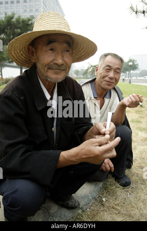 Two gardeners take a pause from work and enjoy a cigarette break in Beijing, China. Stock Photo