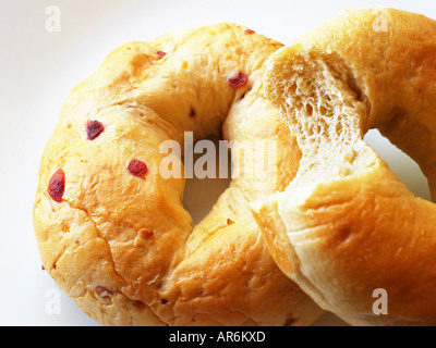 Plain bagel with missing bite atop berry flavored bagel both against a white background. Stock Photo