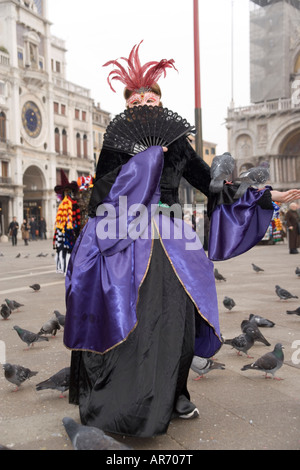 Female Reveller in mask and costume at the Venice carnival in St Mark's Square with St Marks Cathedral behind, Italy Stock Photo