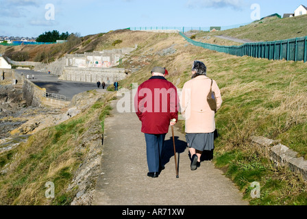 Elderly couple walking on coastal footpath, Barry Island, Vale of Glamorgan, South Wales, UK. Stock Photo