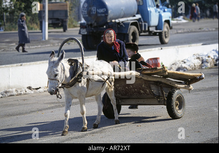 A woman and her grandson drive to town in a donkey drawn cart in Simkent Stock Photo