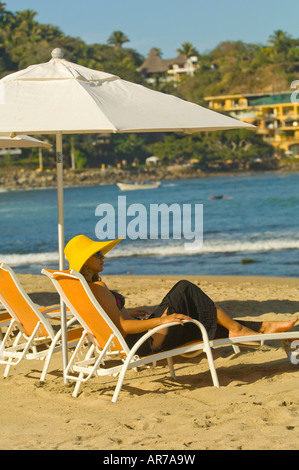 Mexico Riviera Nayarit Village of Sayulita near Puerto Vallarta on the Pacific Ocean woman in yellow hat relaxing in beach chair Stock Photo
