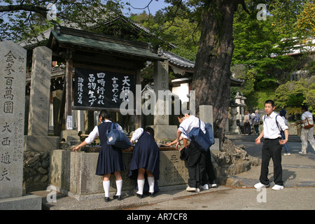 School students on a school trip washing their hands outside Nigatsudo temple in Nara park Japan Asia Stock Photo