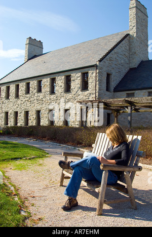 Woman watching golfers while sitting on bench overlooking Whistling Straits Golf Course, Kohler, Wisconsin, USA Stock Photo