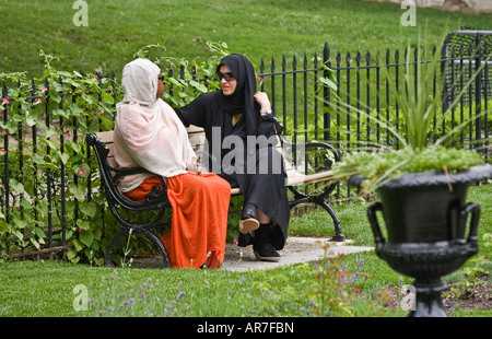 Two Arab women having a conversation in the park Toronto Canada one woman wearing black Abayah Stock Photo