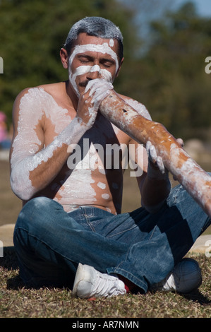 Australian Aborigine wearing face and body paint, playing the didgeridoo Stock Photo