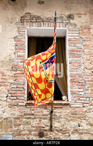 A stuffed teddy bear looks peeks out from a child s bedroom behind a contrade flag in Montepulciano Tuscany Stock Photo