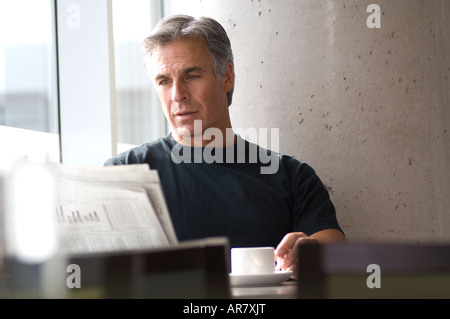 Mature professional man reading newspaper in urban cafe on weekend. Stock Photo