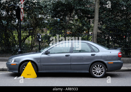 Yellow wheel clamp on parked car London England UK
