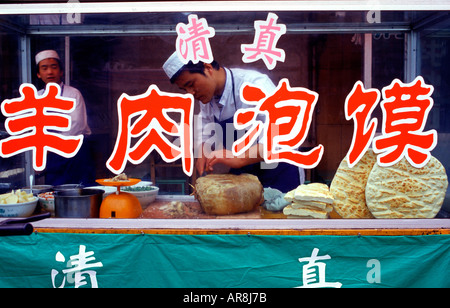Hui men sell Yángròu Pàomó consisting of unleavened flatbread smeared in lamb broth at a food cart in Ningxia Hui Autonomous Region northwest China Stock Photo