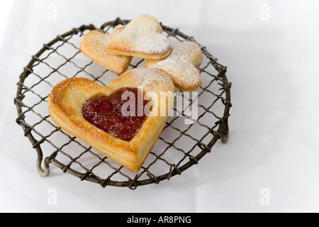 Heart shaped puff pastry Jam Tarts (filled with strawberry jam) - home baked and a served on a vintage wire cooling rack Stock Photo