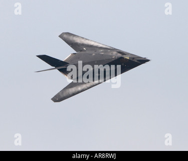 An F-117 Nighthawk stealth fighter in a turn with vapor trails coming off the wings Stock Photo