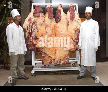 Ethiopian chefs at a wedding reception in Addis Abeba, Ethiopia with sides of raw beef hanging on a rack Stock Photo