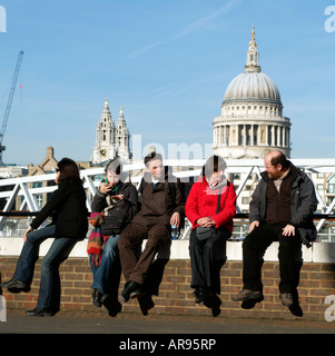 Tourists Sitting on a Wall Backdrop of St Pauls Cathedral London England UK Stock Photo