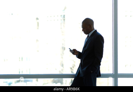 Businessman silhouetted in large office window. Stock Photo