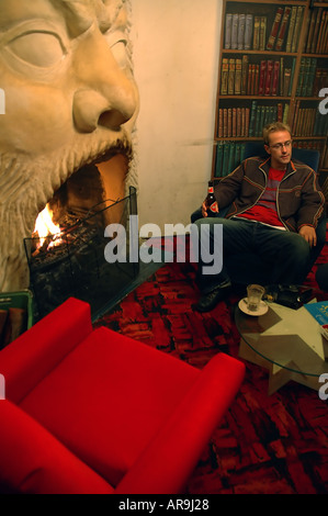 Young man enjoys the imposing fireplace and painted bookshelves of the cosy Luna Cafe