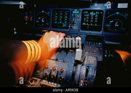 Pilots hand fist fingers on throttles Captains arm with 4 gold bars stripes in cockpit of MD-11 Stock Photo
