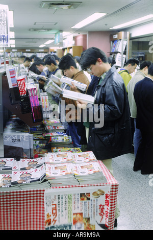 Young Japanese people filling aisles reading magazines in Tokyo bookstore Stock Photo