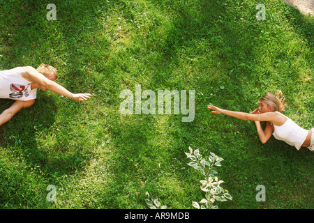 Young man and woman reaching for each other across sunlit green grass Stock Photo