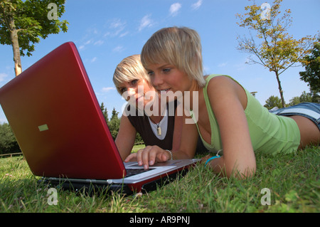 junge Mädchen mit laptop auf wiese - young girls lying in the grass working with notebook Stock Photo