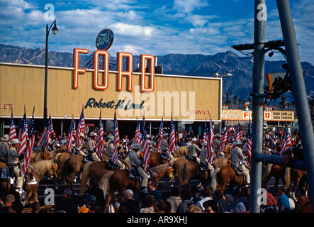 Patriotic horsemen pass Ford garage on Route 66 at Tournament of Roses, Pasadena, California, 1963 Stock Photo