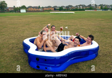 Team members at Keynsham Cricket Club near Bristol England UK relax with beer in a paddling pool when rain stopped play Stock Photo