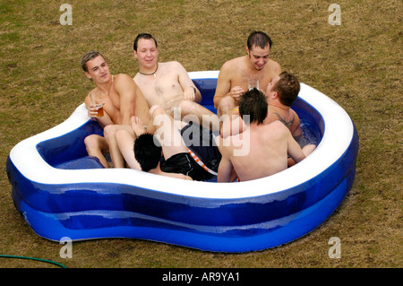 Team members at Keynsham Cricket Club near Bristol England UK GB relax with beer in a paddling pool when rain stopped play Stock Photo