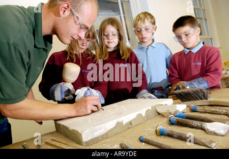 Year 6 pupils cutting letters into a block of sandstone under instruction at The Old Library Cardiff South Wales UK Stock Photo