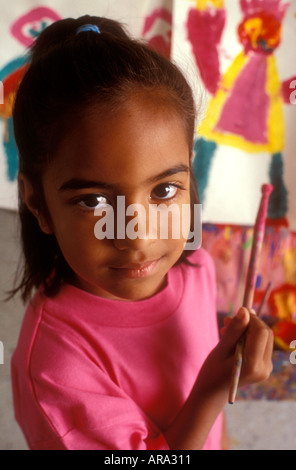 Portrait of infant asian girl aged 4 5 years holding paint brush in school kindergarten art classroom Stock Photo