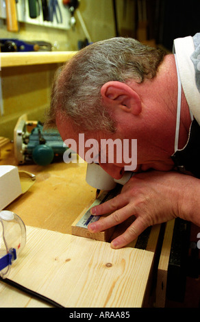 Visually impaired man undertaking DIY tasks at his home using custom made magnifier to aid sight England Stock Photo