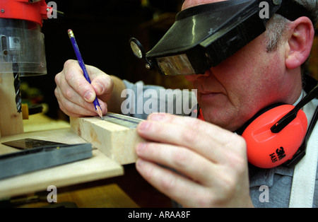 Visually impaired man undertaking DIY task at his home using custom goggles to aid sight in close up work UK Stock Photo