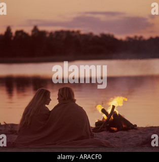 romantic couple relaxing by campfire on beach Stock Photo