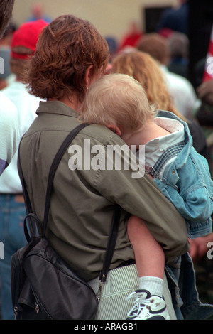 Mother carrying son age 28 and 1 listening to Memorial Day service. St Paul Minnesota MN USA Stock Photo