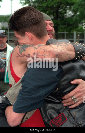 Vietnam biker veteran age 55 embracing man (son?) age 24 at Memorial Day ceremony. St Paul Minnesota MN USA Stock Photo