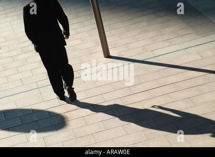 shadow of businessman walking on pavement Stock Photo