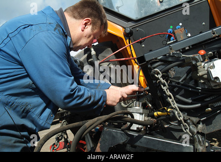 farm worker repairing tractor Stock Photo