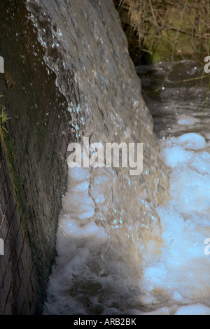Some polluted water falling from a factory to a canal Stock Photo