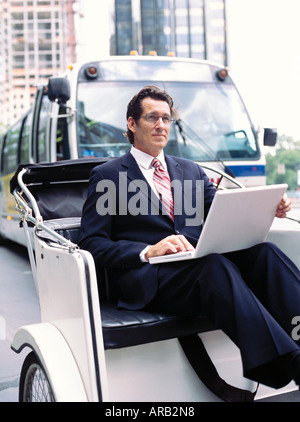 Businessman With Laptop Computer, Sitting in Rickshaw Stock Photo