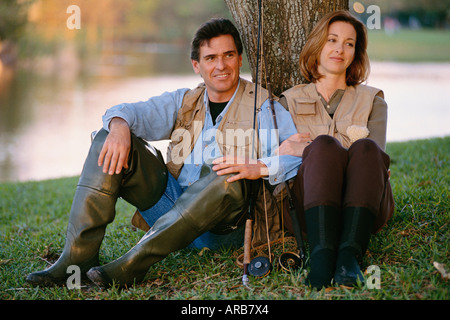 Portrait of Couple Sitting Under a Tree, With Fishing Gear Stock Photo