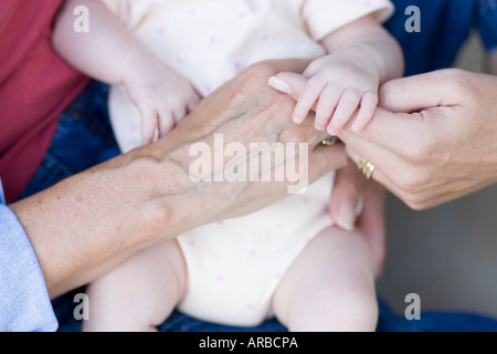 Baby in the Hands of her Mother and Grandmother Stock Photo