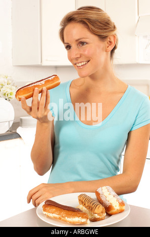 WOMAN EATING CREAM CAKES AND CREAM DOUGHNUTS Stock Photo