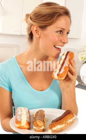 WOMAN EATING CREAM CAKES AND CREAM DOUGHNUTS Stock Photo