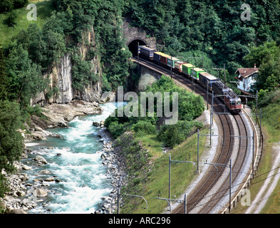 A freight train crosses the River Reuss near Wassen in the Swiss Alps Stock Photo