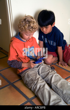 Two boys one Russian born and adopted the other Chinese American play a computer game together in Laguna Niguel CA Stock Photo
